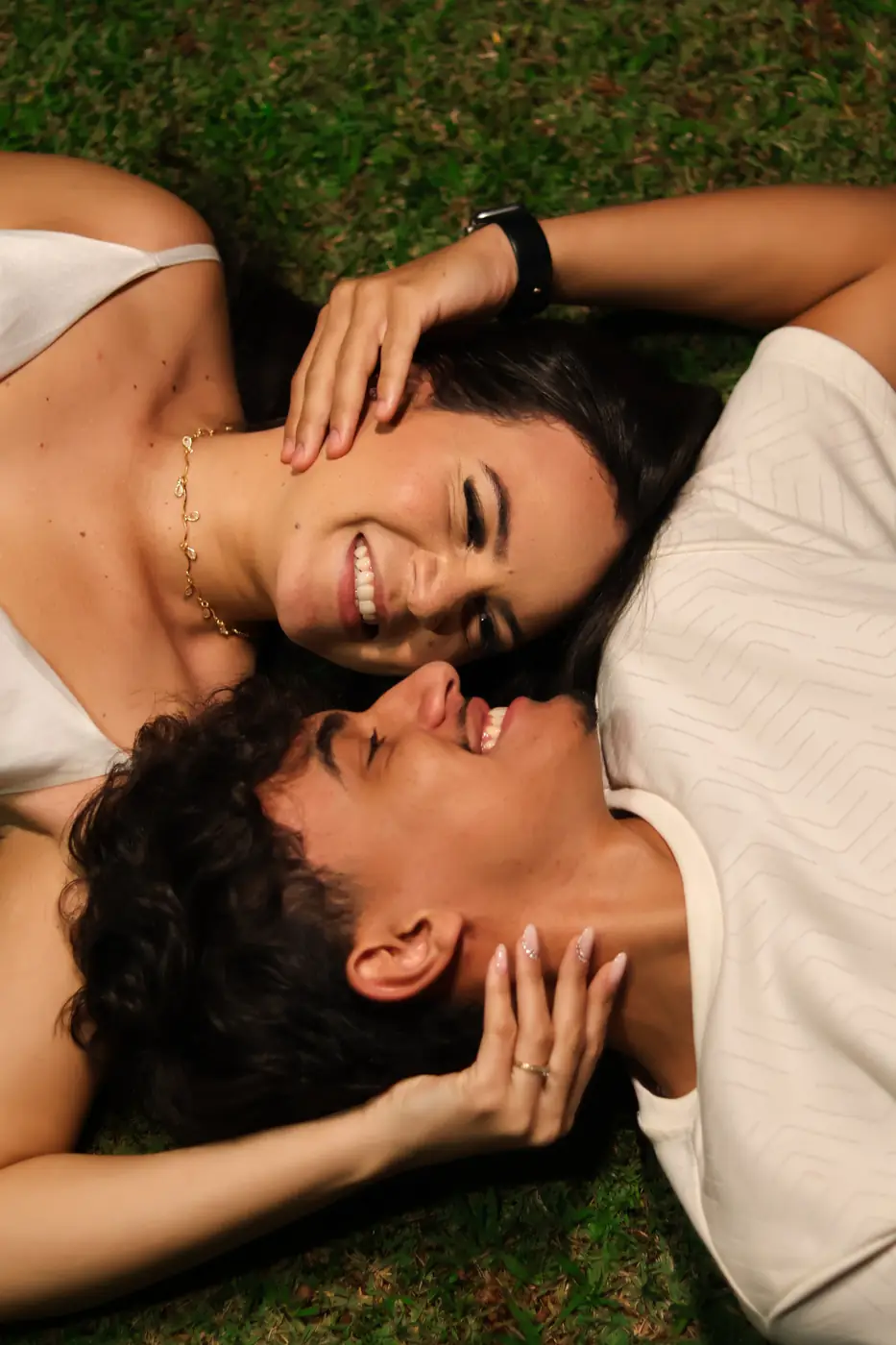 Casal deitado na grama, rindo