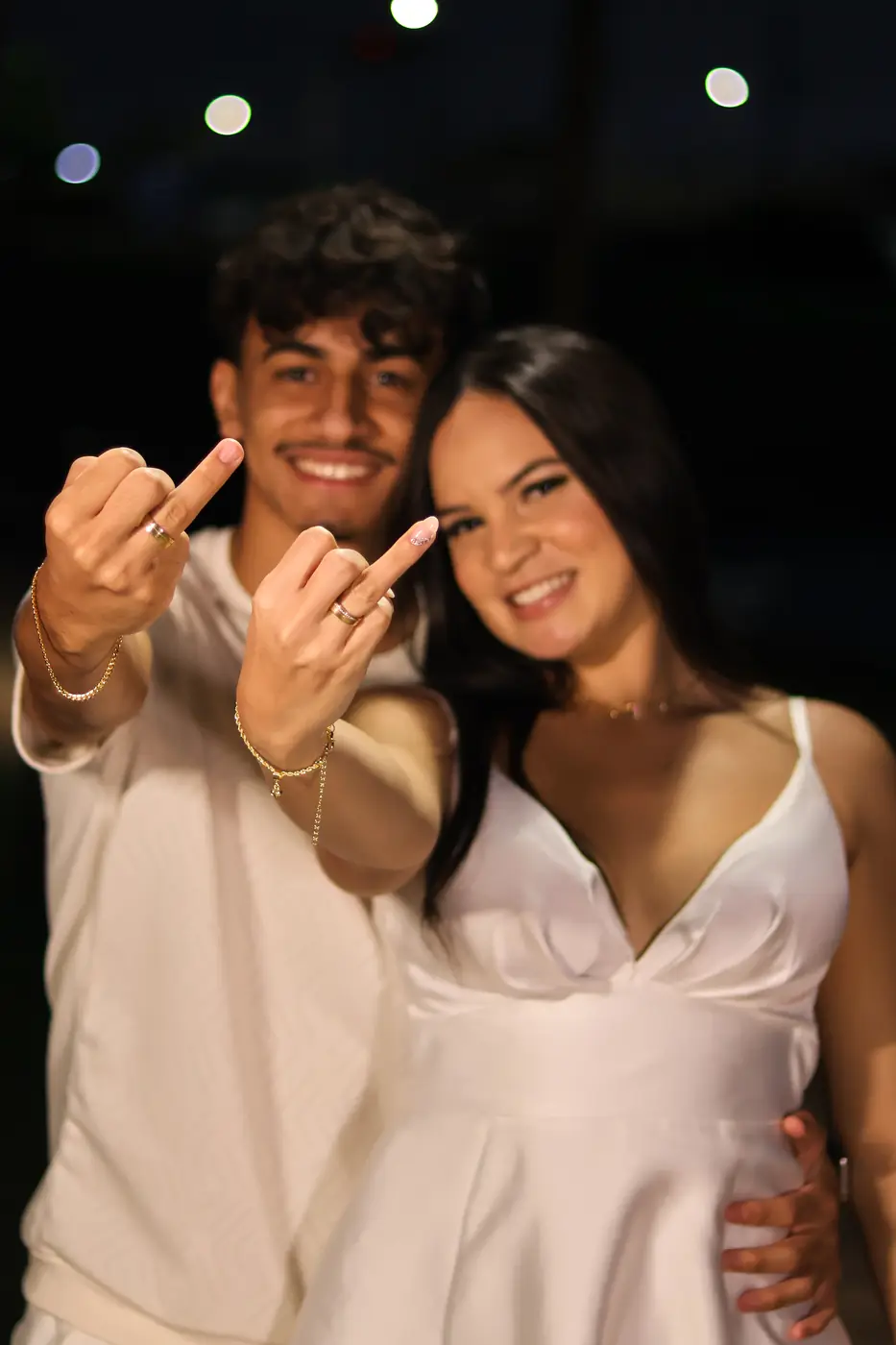 Casal mostrando as alianças à noite